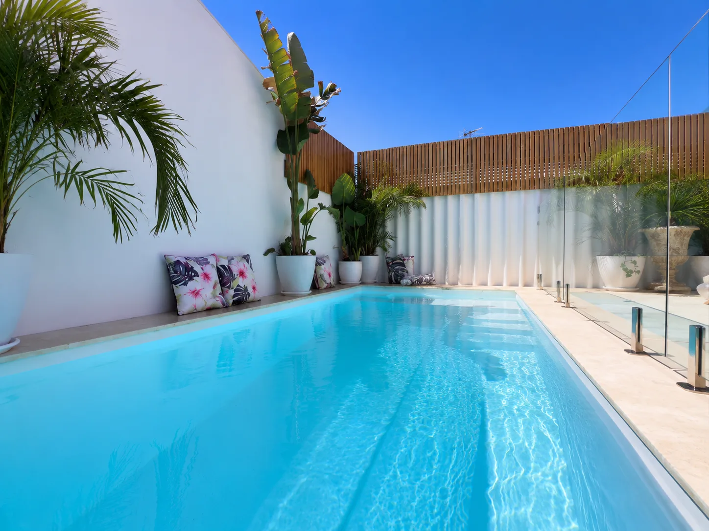 Crystal Retreat pool with glass fencing, travertine paving and tropical planting